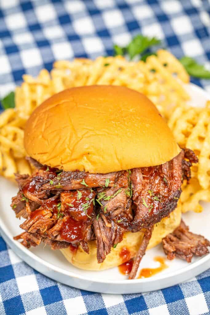 bbq brisket sandwich on a plate with waffle fries