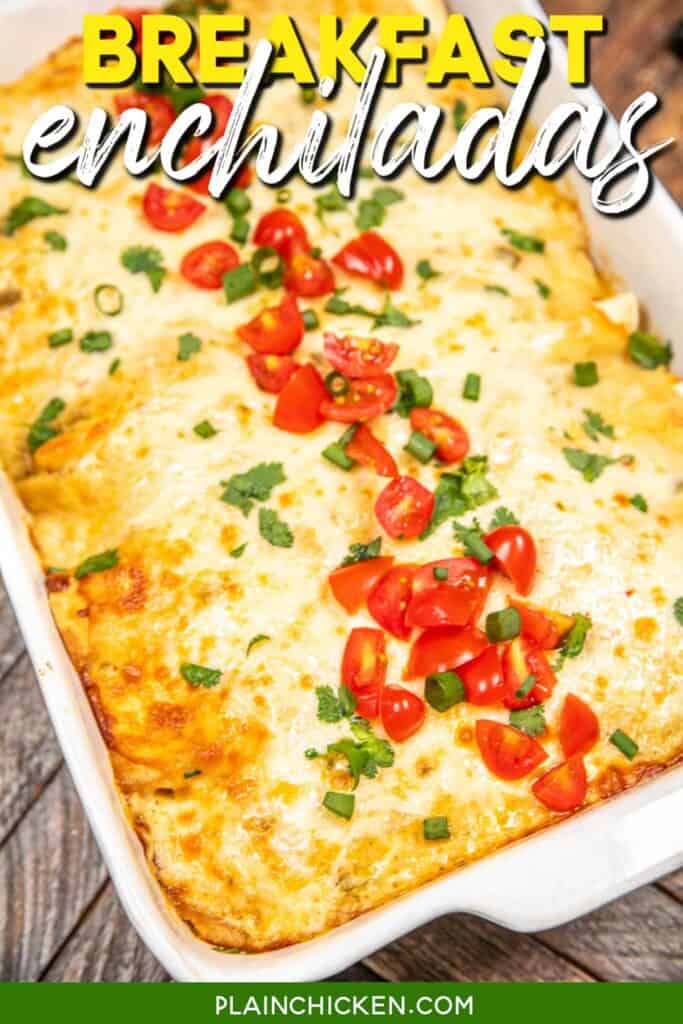 baking dish of breakfast enchiladas topped with tomatoes and green onions on a wooden table with text overlay