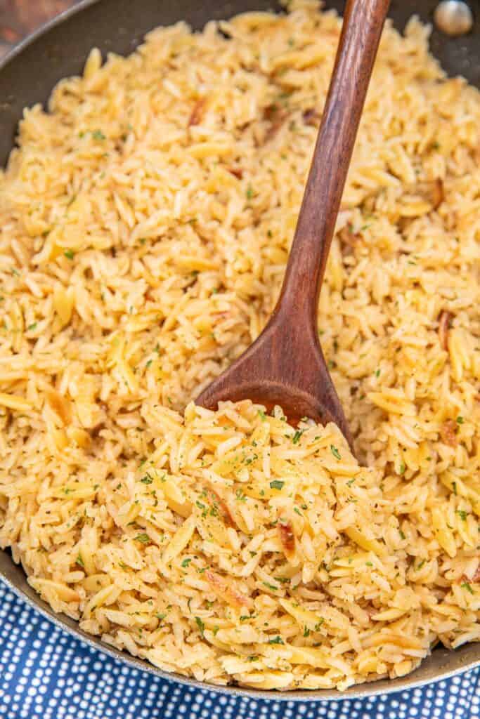 scooping rice pilaf from a skillet