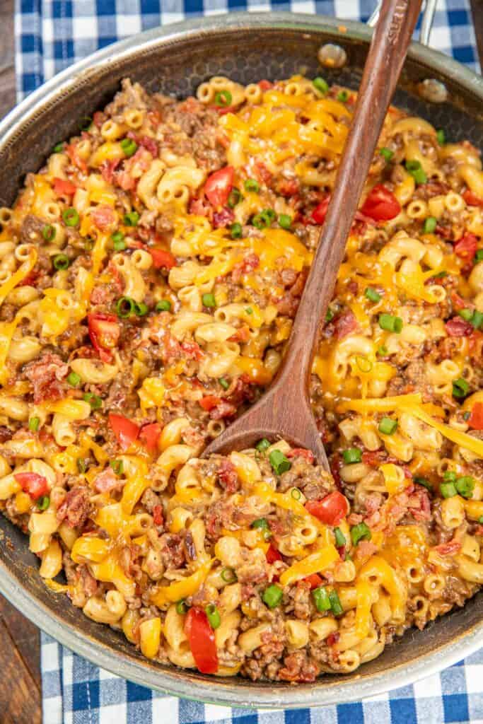 scooping bacon cheeseburger pasta from a skillet with text overlay