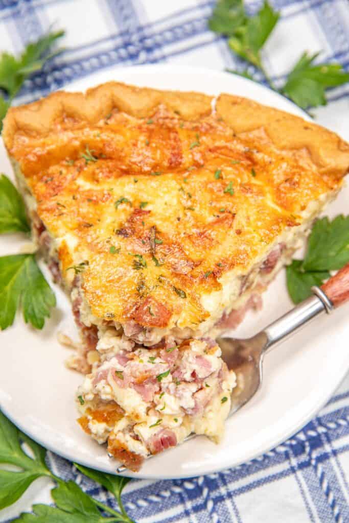 cutting into a slice of ham and cheese quiche