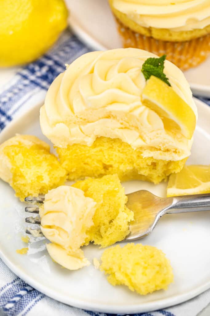 cutting into a lemon cupcake on a plate