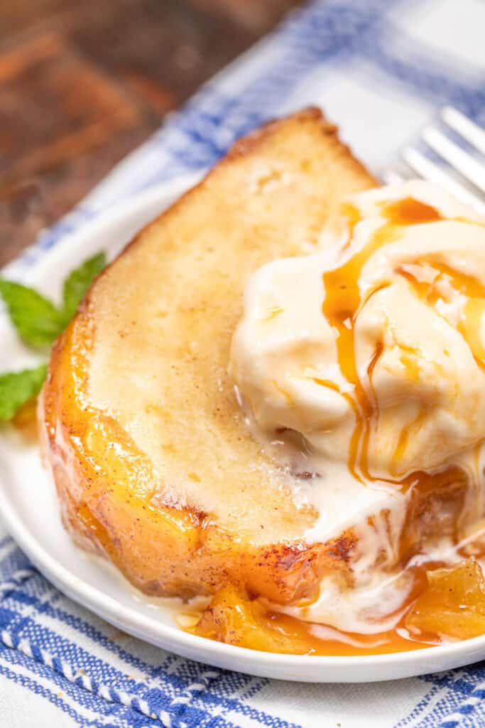 slice of peach cake topped with ice cream and caramel sauce on a plate